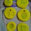 Play-Doh Stamping Activity for Children - circles of yellow Doh with various stamped images and some with holes to hang