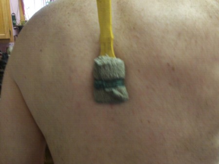 Backscratcher to Apply Lotion - cloth tied onto the scratcher and against someone's back