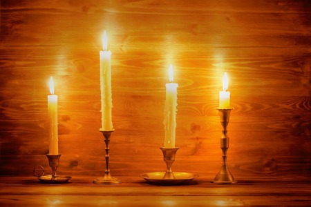 Four different candlesticks with white taper candles.