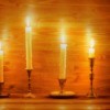 Four different candlesticks with white taper candles.