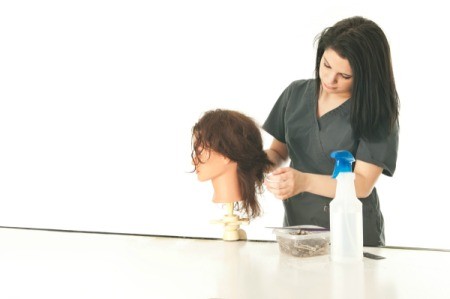 A student working on a hairstyle on a mannequin head.