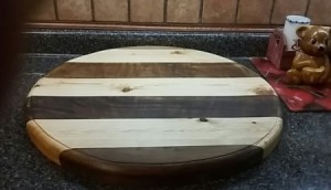 A round wood cutting board, with several colors of wood.