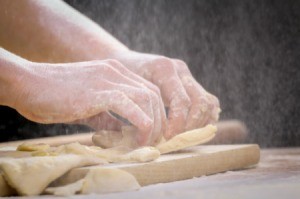 A woman making knots with dough.