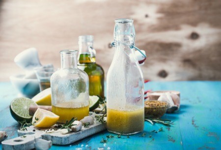 A bottle of oil and vinegar Italian dressing, surrounded by some ingredients.