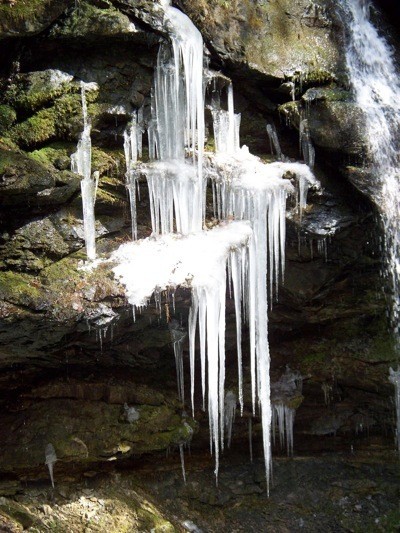 Icicles on rocks near small waterfall.