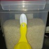 A plastic hook and measuring cup attached to a container of rice.