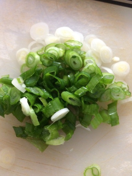 Green onions, sliced on a cutting board.
