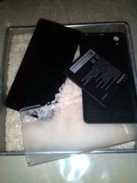A smartphone being buried in rice to dry it out.