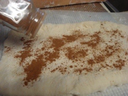 sprinkling cinnamon on dough
