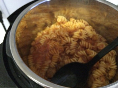 mixing spaghetti, meatballs, and pasta in pot