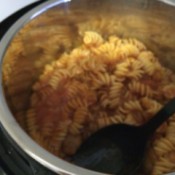 mixing spaghetti, meatballs, and pasta in pot