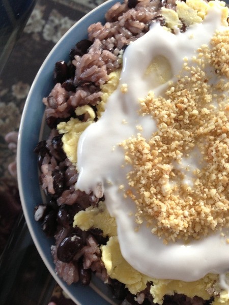 sticky rice and beans in bowl with coconut cream and chopped nuts