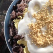 sticky rice and beans in bowl with coconut cream and chopped nuts