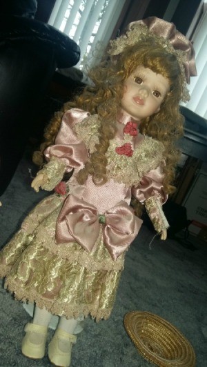 Information and Value of Porcelain Dolls - doll with long curly hair wearing a pink satin period dress with ecru lace at bottom