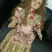 Information and Value of Porcelain Dolls - doll with long curly hair wearing a pink satin period dress with ecru lace at bottom