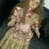 Information and Value of Porcelain Dolls - doll with long curly hair wearing a pink satin period dress with ecru lace at bottom