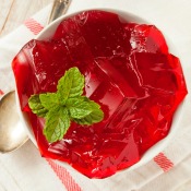 Cubes of red jello in a white dish.