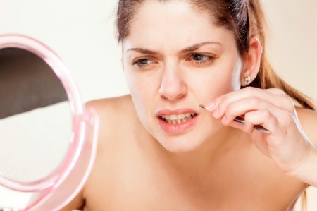A woman removing hair from her upper lip.