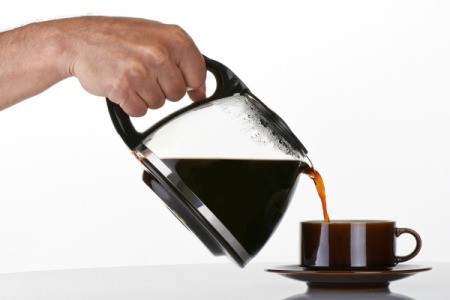 A hand pouring coffee into a cup.