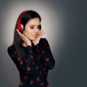 A woman listening to music on red headphones.