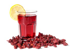 A glass of cranberry juice surrounded with cranberries.