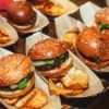 A row of beef sliders, with potato chips.
