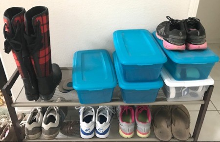 Shoes on a rack and in plastic shoe boxes.