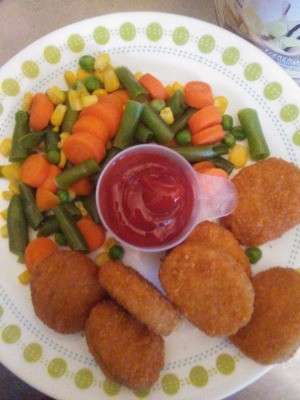 A plate of chicken nuggets with ketchup in a recycled scoop.