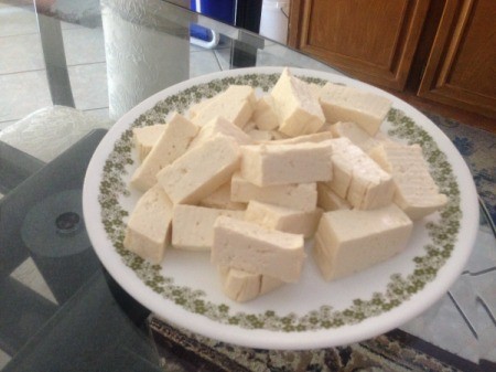 A plate of tofu, chopped into pieces.