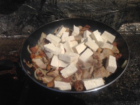 Adding tofu to the stir fry pan.