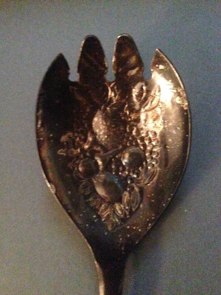 A silver plate spoon with tines.