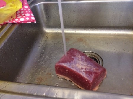 Rinsing corned beef in the sink.