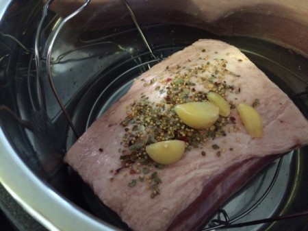 Placing corned beef in the pressure cooker with seasonings.