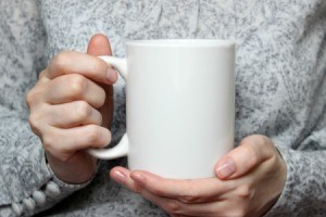 A woman holding a blank coffee cup.