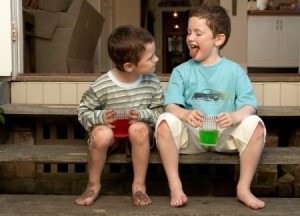 Two boys drinking koolaid outside.