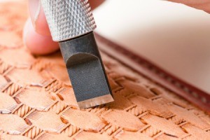 A tool being used to carve a pattern into leather.