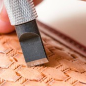 A tool being used to carve a pattern into leather.