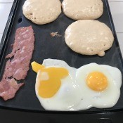 pancakes, bacon and eggs on an electric griddle.
