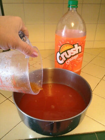 Adding orange soda to jello in bowl.