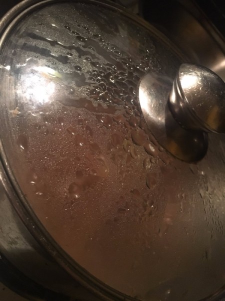 lid on pan of simmering broth for French onion soup.