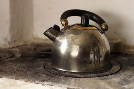 An old metal tea kettle on a stove.