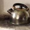 An old metal tea kettle on a stove.