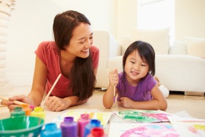 Babysitter and girl Lying On Floor And Painting Picture