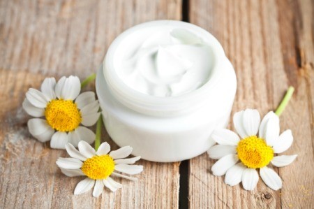 Container with face cream and chamomiles