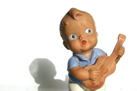 Old rubber doll of a boy playing a guitar.