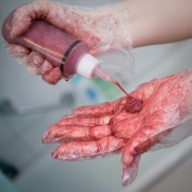 Someone squeezing red hair dye on to their hands.