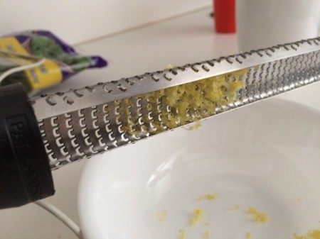 A zester tapping lemon zest into a bowl.