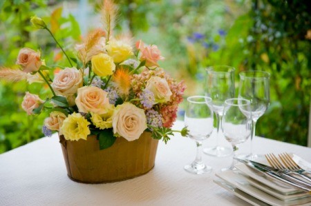 Cheerful bouquet on white table cloth next to place settings.