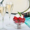 Table with tennis racket and balls, strawberries and champagne.