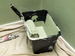 Bucket of green paint on a drop cloth.